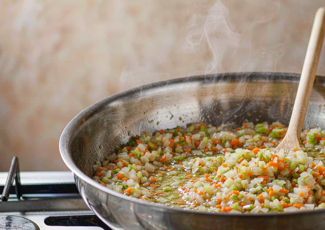 Soffritto of diced onion, carrot, and celery softening in olive oil in a wide heavy pot
