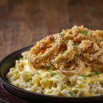 German Kaesespaetzle in a cast-iron skillet with melted cheese and crisp fried onions on top