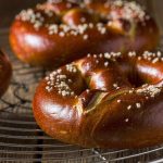 Freshly baked German soft pretzels with dark brown crusts and coarse salt on a wire rack