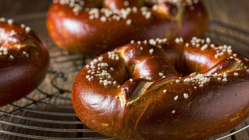 Freshly baked German soft pretzels with dark brown crusts and coarse salt on a wire rack