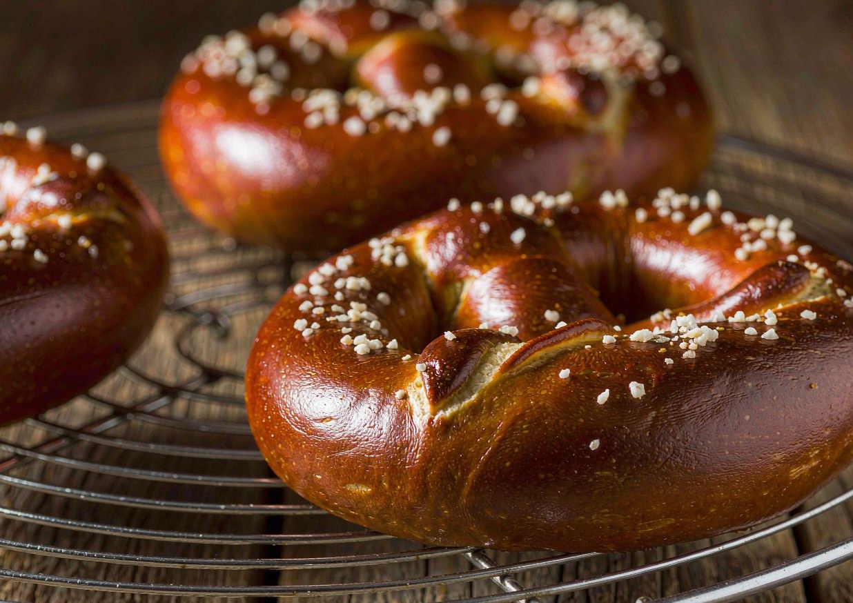 Freshly baked German soft pretzels with dark brown crusts and coarse salt on a wire rack