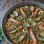 Spanish seafood fideua in a wide paella pan with prawns, clams and toasted noodles