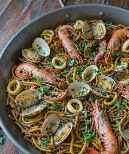 Spanish seafood fideua in a wide paella pan with prawns, clams and toasted noodles