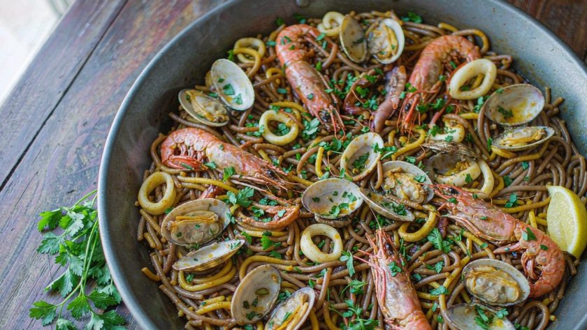 Spanish seafood fideua in a wide paella pan with prawns, clams and toasted noodles